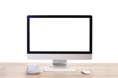 Bilgisayar monitörü, klavye, fare ve bardak bardak beyaz arka plana karşı ahşap masa üzerinde