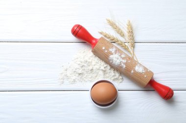 Yuvarlanan iğne, un, çiviler ve yumurta beyaz ahşap masada, düz yerde. Metin için boşluk