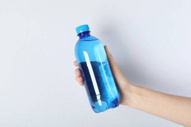 Arka planda plastik su şişesi tutan kadın, yakın plan.