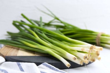 Taze yeşil soğanlar beyaz masada, yakın plan.