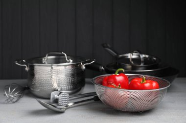 Gri ahşap masada bulaşık takımı, mutfak gereçleri ve sebzeler.