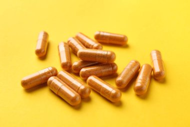 Sarı arka planda birçok zerdeçal kapsülü, yakın plan