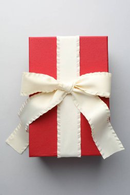 Açık gri arkaplanda bej rengi fiyonklu hediye kutusu, üst görünüm