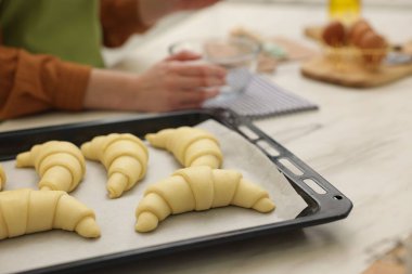 Beyaz mermer masada kruvasan yapan kadın, seçici odaklı.