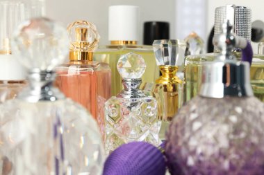 Aydınlık arka planda şişelerde farklı aromatik parfümler, yakın plan.