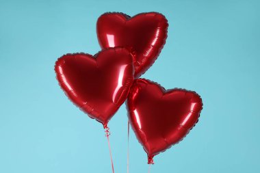 Açık mavi arka planda üç kırmızı kalp şeklinde balon. Sevgililer Günün kutlu olsun.