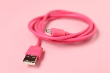Soluk pembe arkaplanda bir USB şarj kablosu.