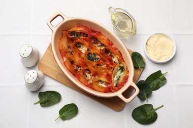 Lezzetli koni makarnası, ricotta peyniri, ıspanak ve domates sosu beyaz fayanslı masada, düz yerde.