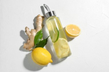 Limonlu limonlu su, taze meyveler, yeşil yapraklar ve beyaz masada zencefil.