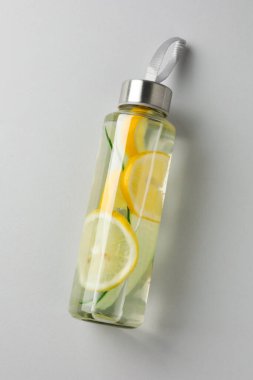 Şişede salatalık olan limonlu su açık gri arka planda, üst tarafta.