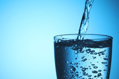 Açık mavi arka planda ferahlatıcı soda bardağına dökülüyor, yakın plan. Metin için boşluk