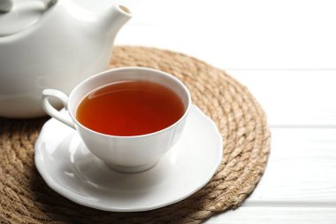 Aromatik siyah çay fincanda ve çaydanlık beyaz ahşap masada, yakın plan