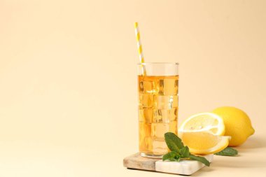 Buzlu çayı bardakta pipet, bej arka planda nane ve limon içerek tazeliyorum. Yakın plan. Metin için boşluk