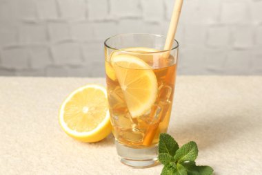 Buzlu çayı saman, nane ve limon dilimleri ile tazeleyerek açık dokulu masada gri arka planda, yakın plan