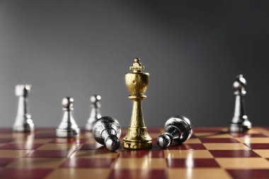 Satranç tahtasındaki gümüş parçaların arasında altın satranç kralı, yakın plan. Rekabet konsepti
