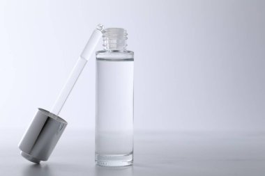 Açık gri masada serum şişesi ve pipeti, yakın plan. Metin için boşluk