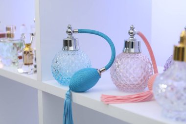 Dükkandaki raflarda farklı lüks parfüm şişeleri var.