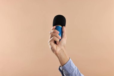 Bej arka planda mikrofonu olan adam, yakın plan.