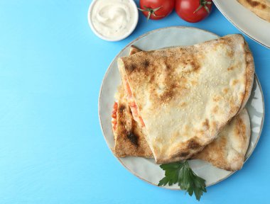 Lezzetli calzone, domates ve sos açık mavi masa, düz yatak. Metin için boşluk