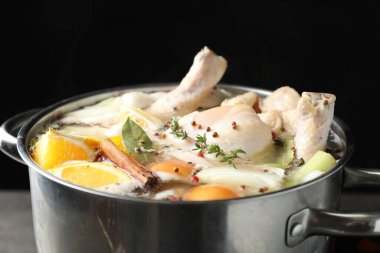 Taze hindi, turunçgiller, kekik ve baharatlar siyah arka planda kaynıyor, yakın plan.