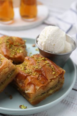 Beyaz ahşap masada ezilmiş fındıklı ve dondurmalı enfes baklava, yakın plan.