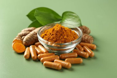 Kabın içinde zerdeçal tozu, yeşil arka planda kök ve kapsüller