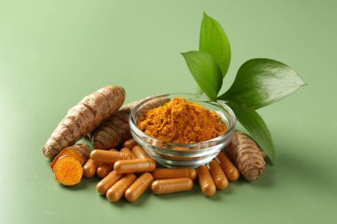 Kabın içinde zerdeçal tozu, yeşil arka planda kök ve kapsüller