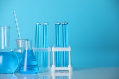 Aynanın yüzeyinde mavi arka planda sıvı bulunan laboratuvar camları. Metin için boşluk