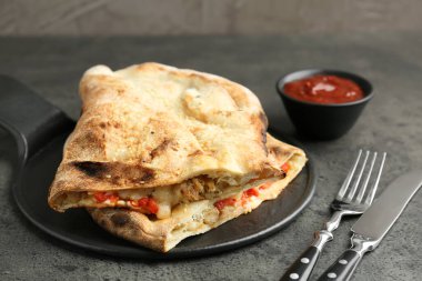 Etli, peynirli, domatesli ve soslu yarım porsiyon leziz calzone, yakın plan.