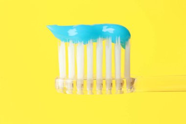 Sarı arka planda diş macunlu diş fırçası, yakın plan.