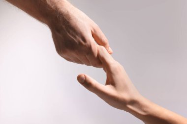Yardım ve destek. Açık gri arka planda el ele tutuşan insanlar, yakın plan.
