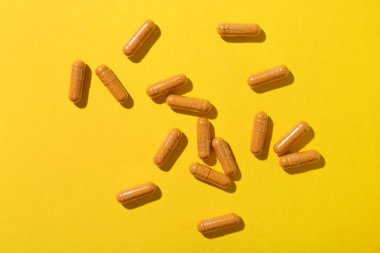 Sarı zemin üzerinde birçok zerdeçal kapsülü, düz yatıyordu