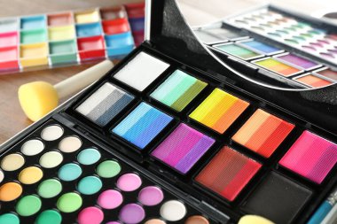 Ahşap arka planda yüz boyaları ve araçlar, yakın plan