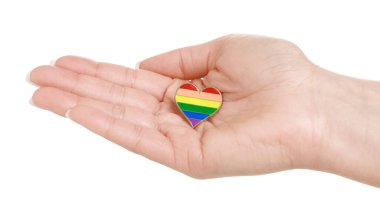 Beyaz arkaplanda LGBT renginde kalp şeklinde iğnesi olan kadın, yakın plan