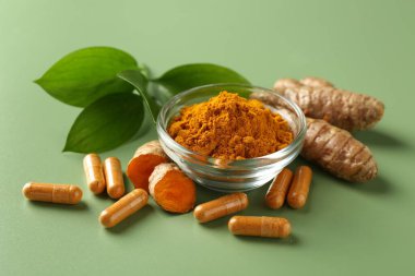 Kâsede zerdeçal tozu, yeşil arka planda kök ve kapsüller, yakın plan.
