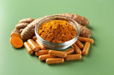 Kabın içinde zerdeçal tozu, yeşil arka planda kök ve kapsüller