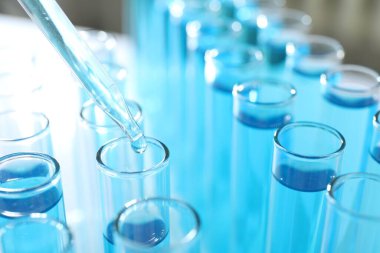 Işık arkaplanındaki test tüplerine sıvı damlatılıyor.