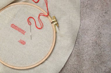 Canvas with embroidery in hoop on grey table, top view. Space for text clipart