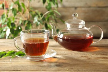 Cam bardakta taze demlenmiş çay ve ahşap masada çaydanlık.