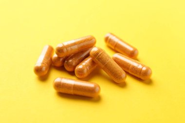 Sarı arka planda birçok zerdeçal kapsülü, yakın plan