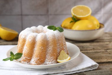 Pudra şekerli lezzetli limonlu pasta, taze meyve dilimi ve ahşap masada nane, yakın plan.