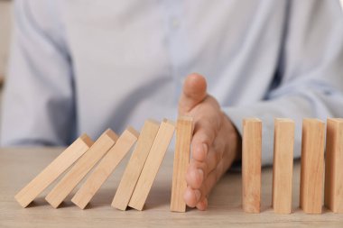 Ahşap blokların masada düşmesini engelleyen adam, yakın plan. Domino etkisi