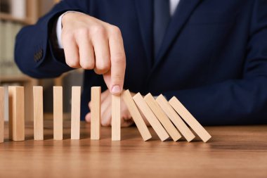 Ahşap blokların masada düşmesini engelleyen adam, yakın plan. Domino etkisi