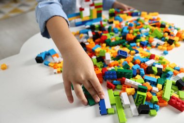 Beyaz masadaki yapı taşlarıyla oynayan kız, yakın plan.