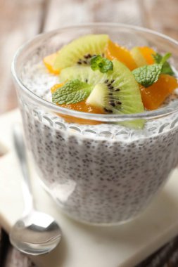 Kivili lezzetli chia pudingi, şeftali ve nane şekeri masada servis edilir, yakın plan.