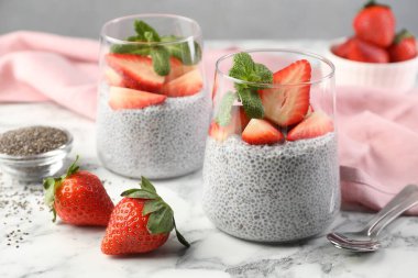 Çilekli lezzetli chia pudingi ve beyaz mermer masada nane şekeri, yakın plan.