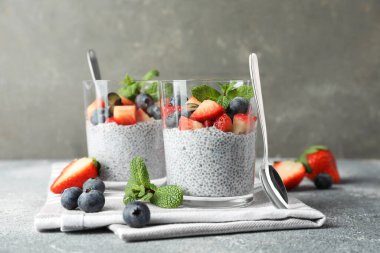 Çilekli lezzetli chia pudingi, yaban mersini ve gri masada nane şekeri.