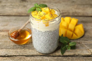 Bardakta mangolu lezzetli chia pudingi, ahşap masada nane ve bal, yakın plan.