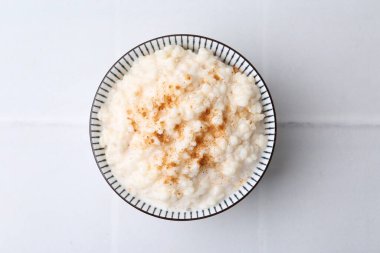 Beyaz fayanslı masada tarçınlı lezzetli sütlaç.