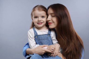 Gri arka planda sevimli küçük kızı olan güzel bir anne.